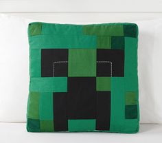 a green and black pillow sitting on top of a white couch next to pillows in the shape of squares