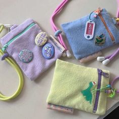 three small purses are sitting next to each other on a table with ear buds