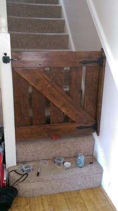 an open wooden gate sitting on top of a carpeted floor next to a stair case