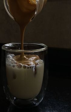 an orange being drizzled over some liquid in a glass cup on a table