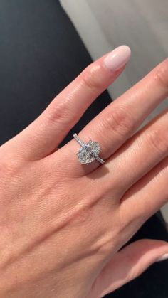 a woman's hand with a diamond ring on top of her finger and the other hand holding an engagement ring