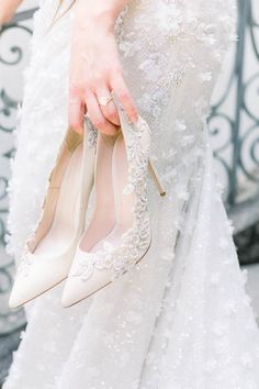 a woman is holding her wedding shoes