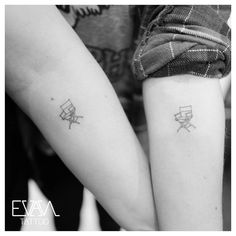 two people with matching tattoos on their arms, one is holding the other's arm