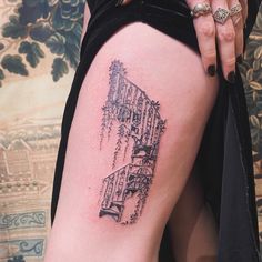 a woman's thigh with a tattoo of a building and trees on the side