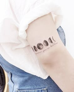 a woman with a tattoo on her arm that reads moon phases and the word love is written in cursive font