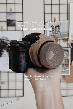 a person holding up a camera in front of a wall with pictures and words on it