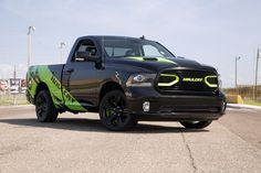 a black and green truck parked on the side of a road in a parking lot