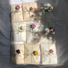 six wrapped gift boxes with flowers tied to them on a sheet of white paper in the shape of squares