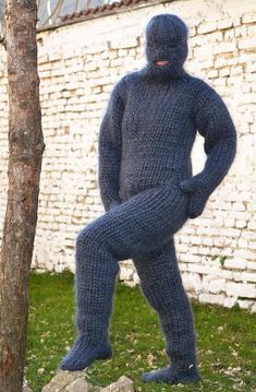 a knitted man standing next to a tree