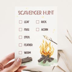 a hand holding up a scavenger hunt card with fire and wood on it