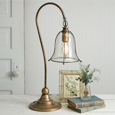 a lamp that is on top of a table next to some books and a plant