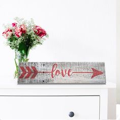 a vase filled with flowers sitting on top of a white dresser next to a sign that says love