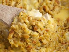 a wooden spoon scooping some food out of a casserole dish with cheese