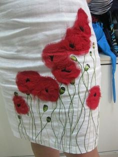 a woman wearing a white skirt with red flowers painted on the side and green stems