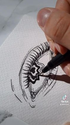 someone is drawing an eye with a black marker