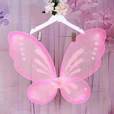 a pink butterfly shaped object hanging on a white hanger with flowers in the background