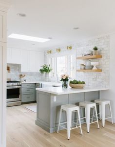 a kitchen with white and gray cabinets, counter tops and stools in front of the island