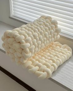 a stack of pillows sitting on top of a window sill next to a window