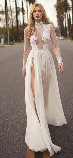 a woman is walking down the street wearing a white dress with sheer cutouts and high slit