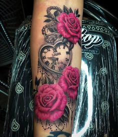 a woman's arm with pink roses and an old pocket watch tattoo on it