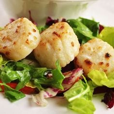 some scallops and lettuce on a white plate