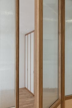 an empty room with wooden floors and glass doors on the wall, looking into another room