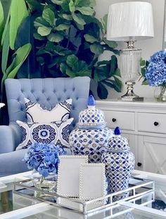 a living room with blue and white decor on the walls, furniture and flowers in vases