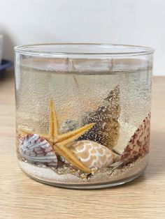 a glass jar filled with sand and sea shells