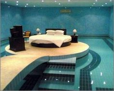 a bed sitting on top of a swimming pool next to a night stand and speakers