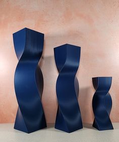 three tall blue vases sitting next to each other on a white floor in front of a pink wall