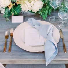 a place setting with napkins, silverware and flowers on the table for an elegant wedding reception