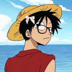 a man with glasses and a straw hat on standing in front of the ocean looking at something