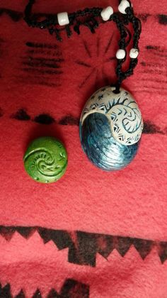 a necklace with a green bead and a white ceramic ball on a red background