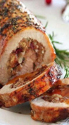 a meatloaf is cut into slices on a white plate with rosemary sprigs