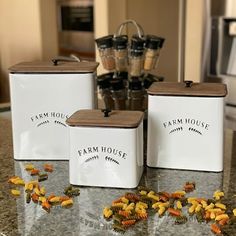 three white canisters sitting on top of a counter next to some yellow flowers