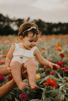 a woman holding a baby in a field of flowers