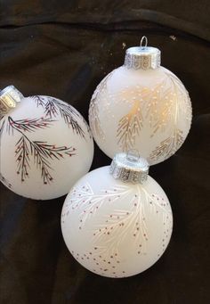 three white christmas ornaments on a black background