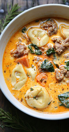 a white bowl filled with soup and dumplings on top of a wooden table,