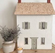 a white doll house sitting on top of a wooden table