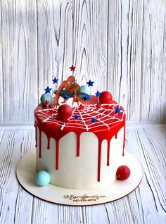 a birthday cake with red, white and blue icing on the top is decorated like a spiderman