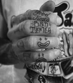 a person with tattoos on their fingers holding something in his hand and the words good times bad times written on them