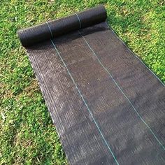 a roll of black tarp laying on the grass