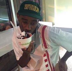 a man eating an ice cream sundae with a green hat on and holding a spoon in his hand