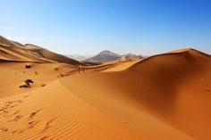 two people are walking in the sand dunes