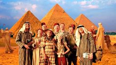 a group of people standing next to each other in front of pyramids