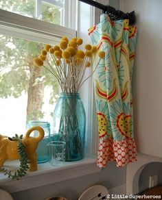 a window sill filled with vases and yellow flowers next to a blue curtain