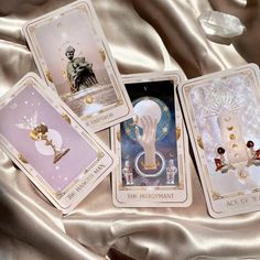 four tarot cards with angels on them sitting next to each other in front of a satin surface