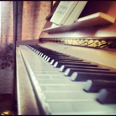 an old piano is sitting in front of a window