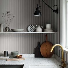 a kitchen with black and white striped wallpaper, wooden cutting board on the counter