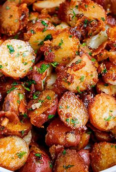 a bowl filled with potatoes covered in sauce and parsley